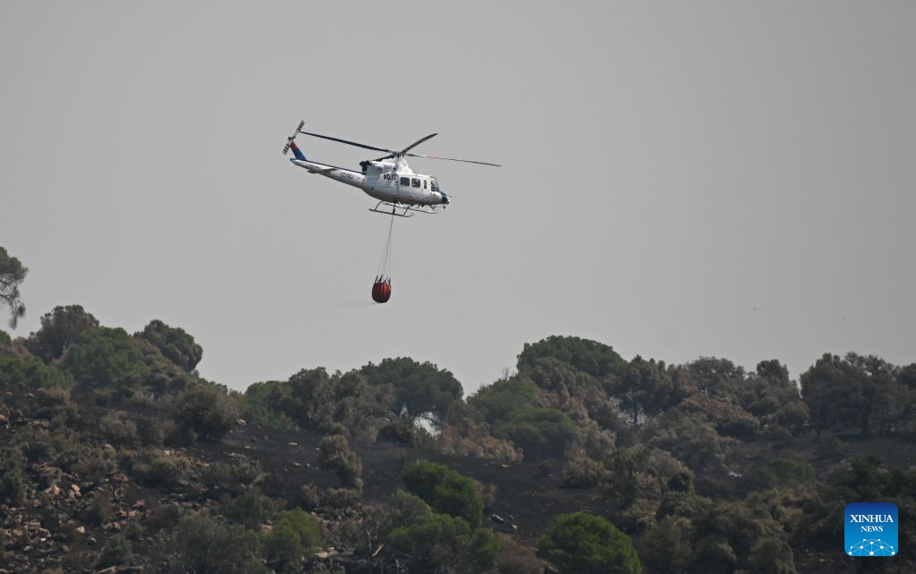A firefighting helicopter carries water in the Madrid region, Spain, July 29, 2026. Spanish Prime Minister Pedro Sanchez announced on Thursday the end of the national emergency declared over wildfires in the province of Avila and the Madrid region, as fires in the two areas have largely stabilized, while blazes remain active elsewhere amid a new heatwave and strong winds. (Xinhua/Cheng Min)