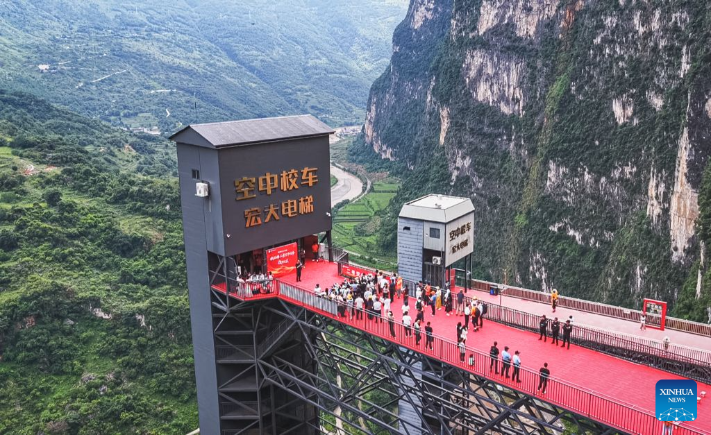 An aerial drone photo taken on July 31, 2026 shows a cliff elevator (L) newly made operational at Nizhu River Grand Canyon in Nizhuhe Village of Puli Township, Xuanwei City, southwest China's Yunnan Province. A 288-meter-high cliff elevator began operation recently at Nizhu River Grand Canyon, side by side to another one of its kind already in service since 2022. This is expected to further facilitate local students' trips to their schools.
Nizhuhe Village is a small hamlet nestled in a deep valley carved by the Nizhu River meandering from south to north. In the past, the shortest route from the valley floor to the mountaintop was a steep cliffside path, and the round trip took nearly six hours. Children and their parents had to make the arduous journey at least once every 10 days.
In 2022, a significant change came to this challenging journey. Nizhu River Grand Canyon scenic area was completed and opened, with a 268-meter-high cliff elevator and a cable car system put into operation. The facilities are open free of charge to local villagers.
Today, the combination of sightseeing shuttle vehicles, elevators and cable cars has shortened students' journey to school to about 30 minutes. A dedicated passage has also been set up for the students, with police officers and dedicated staff members as their guardians along the trips. (Xinhua)