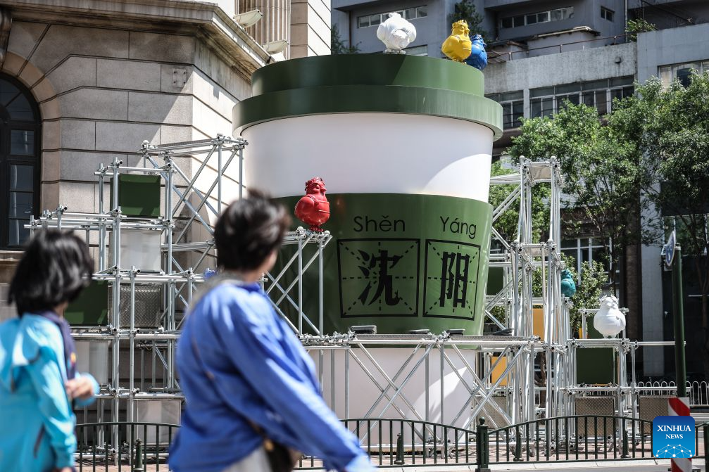 People walk past an outdoor art installation on Bajing Street, Shenyang City, northeast China's Liaoning Province, Aug. 1, 2026. A pack of coffee shops of varying styles on Bajing Street in Shenyang have breathed new life into the old city. Once quiet but obsolete, this historic street is now a vibrant new landmark of culture and tourism that attracts thousands of young visitors every day. Each coffee shop here tells a different story of how a city grows in time. (Xinhua/Pan Yulong)