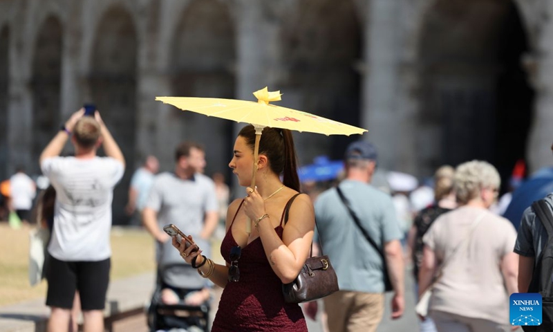 A woman shields herself with a parasol while walking near the Colosseum amid a heatwave in Rome, Italy, June 21, 2026. (Xinhua/Li Jing)


