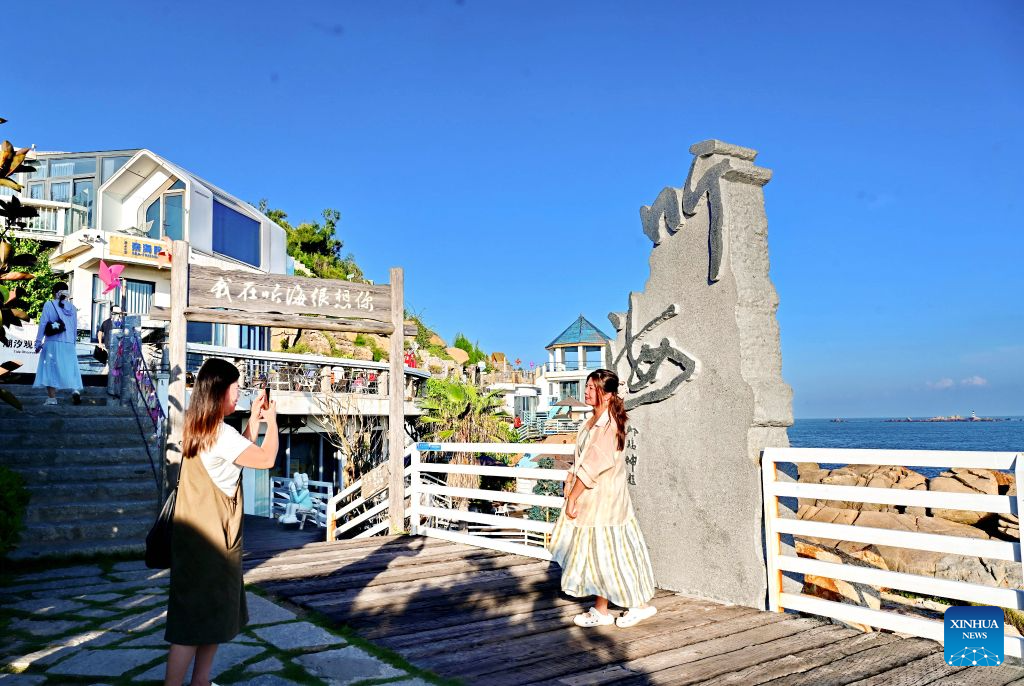Tourists take photos at a scenic spot in Dazuo Village of Hui'an County, southeast China's Fujian Province, Aug. 17, 2026. Dazuo Village is surrounded by the sea on three sides. In recent years, the village has focused on cultivating the traditional customs, launching experiential activities such as net weaving and travel photography to attract tourists. (Xinhua/Lin Shanchuan)