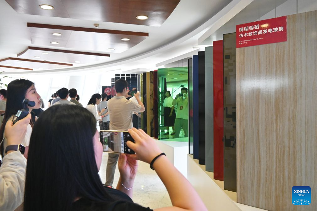 Visitors take photos of different types of power-generating glass at the Bengbu Glass Industry Design and Research Institute of the China National Building Material Group Co., Ltd. in Bengbu, east China's Anhui Province, Aug. 8, 2026. Rooted in its glass industry, Bengbu has in recent years made breakthroughs in core technologies, successfully developed new glass products such as ultra-thin display glass and hollow glass microspheres, and established a complete industrial chain from quartz sand to end-user applications. (Photo by Lin Qiujin/Xinhua)