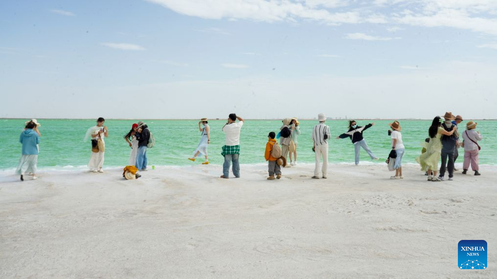 Tourists visit the Qairhan salt lake in Golmud, northwest China's Qinghai Province, July 9, 2026. The Qairhan salt lake, with a total area of 5,856 square kilometers, has been the largest potash fertilizer producing base in China. (Xinhua/Wang Yan)
