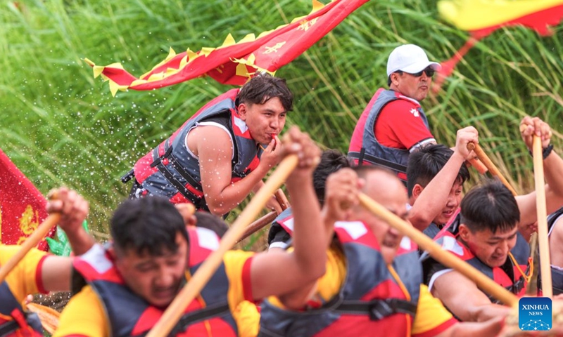 Anwar Kurban (L top) and his teammates compete during a trial match of the 2026 dragon boat race on Hongyan River in Korla City, northwest China's Xinjiang Uygur Autonomous Region, June 19, 2026. (Photo by Ai Houwei/Xinhua)