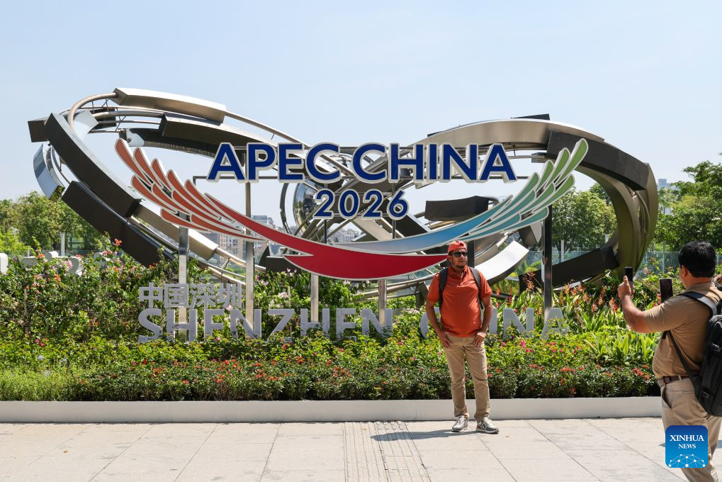 A foreign tourist poses for photos with a themed installation at the east square of the Shenzhen North Railway Station in Shenzhen, south China's Guangdong Province, Aug. 10, 2026. With themed bulletin boards, outdoor posts, decorations and installations, Shenzhen marked on Monday the 100-day countdown to the 33rd Asia-Pacific Economic Cooperation (APEC) Economic Leaders' Meeting. (Xinhua/Liang Xu)