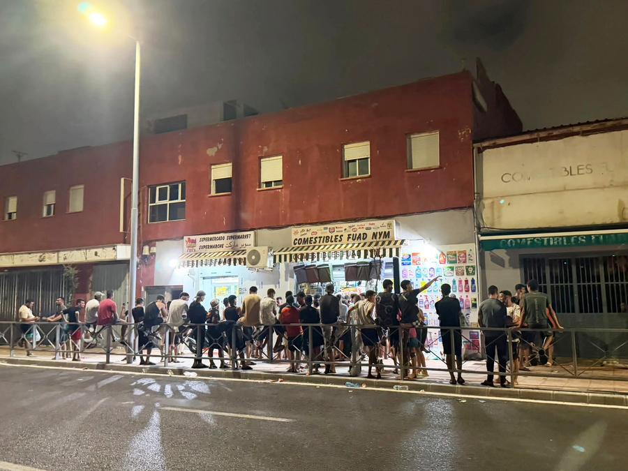 Irregular migrants gather outside a convenience store in Spain's North African enclave of Ceuta, on July 30, 2026. (Photo by Liu Wenyong/Xinhua)