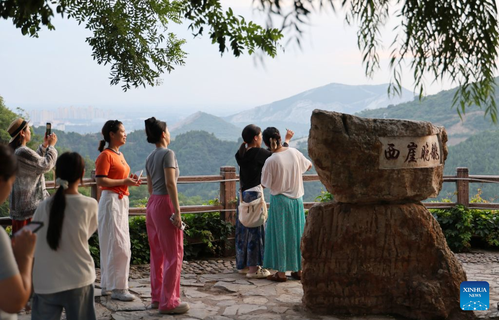 Visitors enjoy the sunset in Xijingyu Village, Jizhou District of north China's Tianjin Municipality, Aug. 4, 2026. During summer vacation, Xijingyu Village has attracted lots of visitors. Known as the Stone Village, it is famous for its distinctive houses and alleys built of stones. (Xinhua/Li Ran)