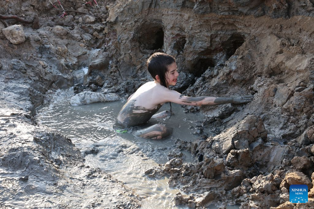 A boy covers himself with mineral-rich mud at a Dead Sea resort, east of Jerusalem, Aug. 5, 2026. People visit the Dead Sea resort as high temperatures sweep across Israel and the Palestinian territories. (Photo by Gil Cohen Magen/Xinhua)
