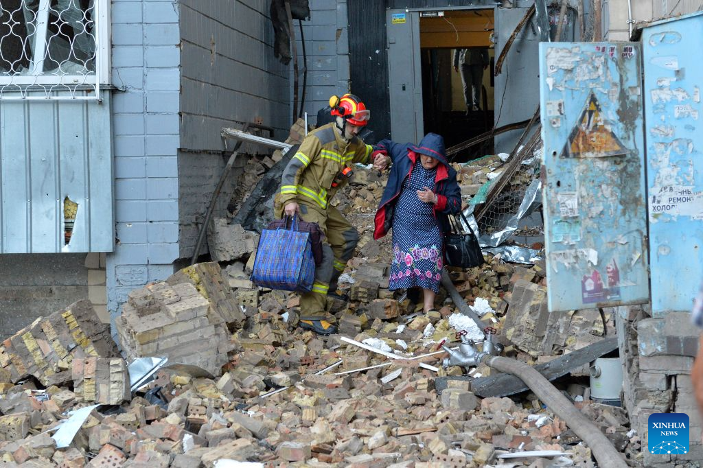A rescuer helps a woman evacuate from a building damaged in a Russian overnight missile and drone attack in Kiev, Ukraine, Aug. 20, 2026. A Russian overnight missile and drone attack hits Kiev, Ukraine, on August 20, 2026. (Photo by Peter Druk/Xinhua)