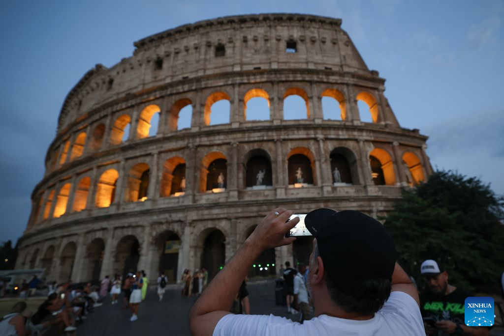 A tourist takes photos of the Colosseum with lights decorated in Rome, Italy, July 28, 2026. (Xinhua/Wang Kaiyan)