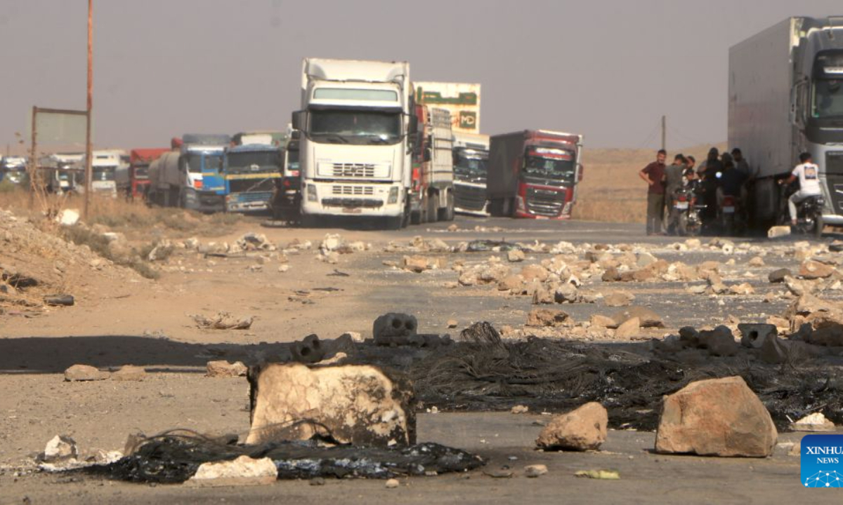 Vehicles are stranded behind rocks and other obstacles near Tal Tamr in Hasakah province, northeastern Syria, Sept. 14, 2026. Residents blocked road to protest increases in fuel prices in Syria. (Str/Xinhua)