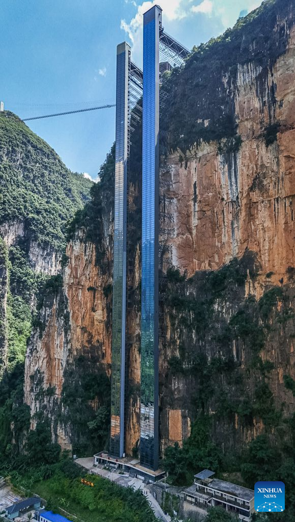 An aerial drone photo taken on July 31, 2026 shows two cliff elevators at Nizhu River Grand Canyon in Nizhuhe Village of Puli Township, Xuanwei City, southwest China's Yunnan Province. A 288-meter-high cliff elevator began operation recently at Nizhu River Grand Canyon, side by side to another one of its kind already in service since 2022. This is expected to further facilitate local students' trips to their schools.
Nizhuhe Village is a small hamlet nestled in a deep valley carved by the Nizhu River meandering from south to north. In the past, the shortest route from the valley floor to the mountaintop was a steep cliffside path, and the round trip took nearly six hours. Children and their parents had to make the arduous journey at least once every 10 days.
In 2022, a significant change came to this challenging journey. Nizhu River Grand Canyon scenic area was completed and opened, with a 268-meter-high cliff elevator and a cable car system put into operation. The facilities are open free of charge to local villagers.
Today, the combination of sightseeing shuttle vehicles, elevators and cable cars has shortened students' journey to school to about 30 minutes. A dedicated passage has also been set up for the students, with police officers and dedicated staff members as their guardians along the trips. (Xinhua)