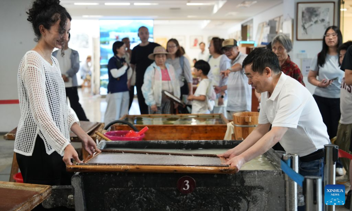 A foreign tourist learns to make Xuan paper in Jingxian County, east China's Anhui Province, on July 31, 2026. (Xinhua)
