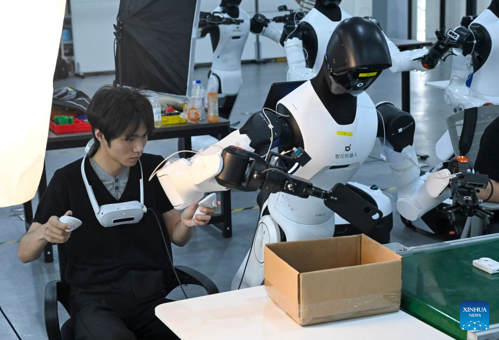 A staff member trains a robot to sort items at Maniformer, a physical AI data service platform, in Shanghai, east China, Aug. 5, 2026. In Shanghai's tech companies like AGIBOT and Maniformer, embodied intelligence robots are trained in household, retail, sorting, production and other real-world scenarios, to advance their AI capabilities for real-life use. (Xinhua/Chen Haoming)