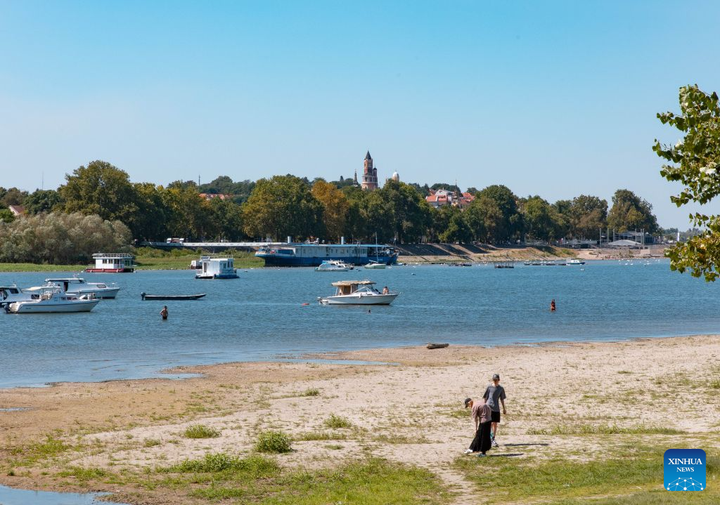 People take a stroll on the bank of the Danube River in Belgrade, Serbia, on Aug. 16, 2026. Riverbed was exposed as the water level of the Danube River approached record-low by severe drought. (Photo by Wang Wei/Xinhua)