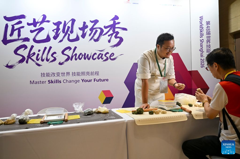 A media staff member (R) tries making mooncakes at the media center of the 48th WorldSkills Competition in Shanghai, east China, Sept. 21, 2026. The 48th WorldSkills Competition is scheduled to take place from September 22 to 27 in Shanghai. (Xinhua/Chen Haoming)