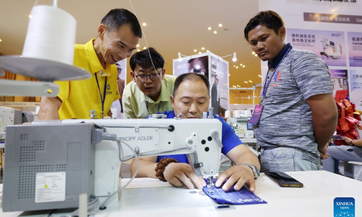 A man tries a sewing machine during an international industrial expo in Phnom Penh, Cambodia, Aug. 15, 2026. A wide variety of advanced Chinese tech and manufacturing firms showcased cutting-edge machinery, automation, and innovative production solutions at a major international industrial exhibition here in Cambodia's capital. (Photo by Sovannara/Xinhua)
