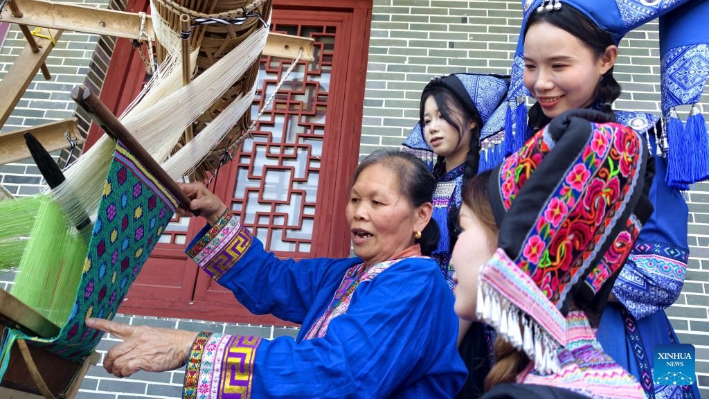 Craftswomen demonstrate Zhuang brocade making skills to tourists in Xincheng County, Laibin City of south China's Guangxi Zhuang Autonomous Region, May 5, 2026. Known for its vibrant colors and auspicious patterns like dragons and phoenixes, Zhuang brocade is one of the four famous brocades in China. In 2006, Zhuang brocade weaving skill, a craft dating back to the Han Dynasty (202 BC-220 AD), was included in the first batch of national intangible cultural heritage list. Over the years, successive generations of Zhuang brocade weavers in Guangxi, while adhering to ancient techniques, have been constantly innovating the brocade weaving skills and the product development. A wide variety of products have been made from the Zhuang brocade, which are sold well both at home and abroad. (Photo by Fan Shaoguang/Xinhua)