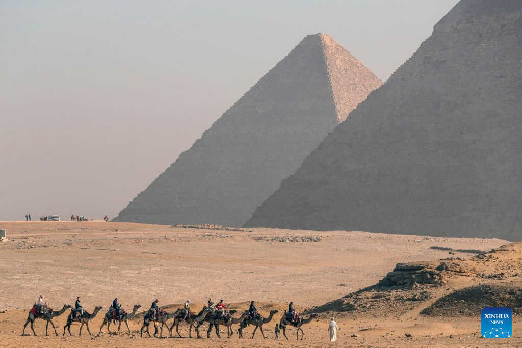 Tourists ride camels at the Pyramids scenic spot in Giza, Egypt, Aug. 16, 2026. (Xinhua/Ahmed Gomaa)