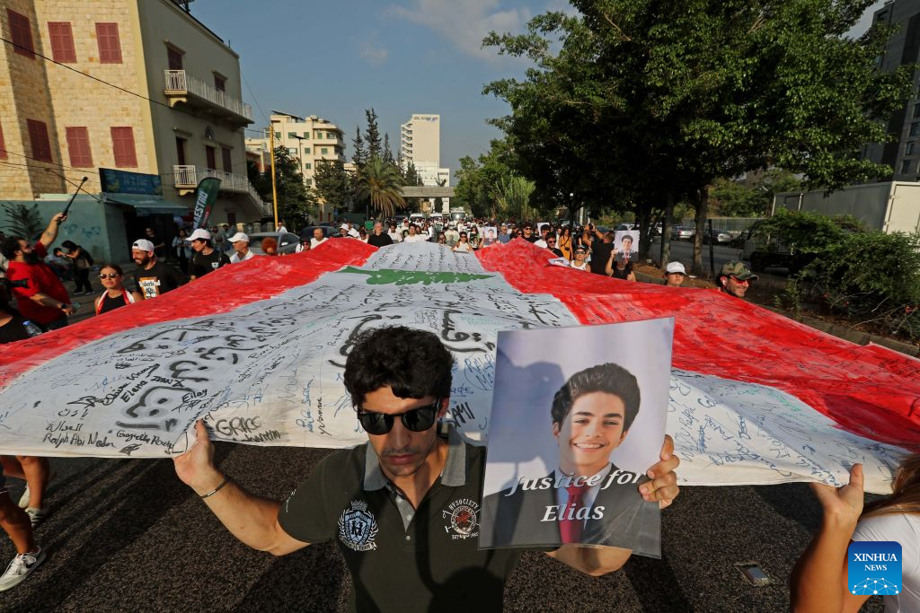 People hold a national flag and portraits of the victims in commemoration of the sixth anniversary of the 2020 Beirut port blasts in Beirut, Lebanon, Aug. 4, 2026. (Xinhua/Bilal Jawich)