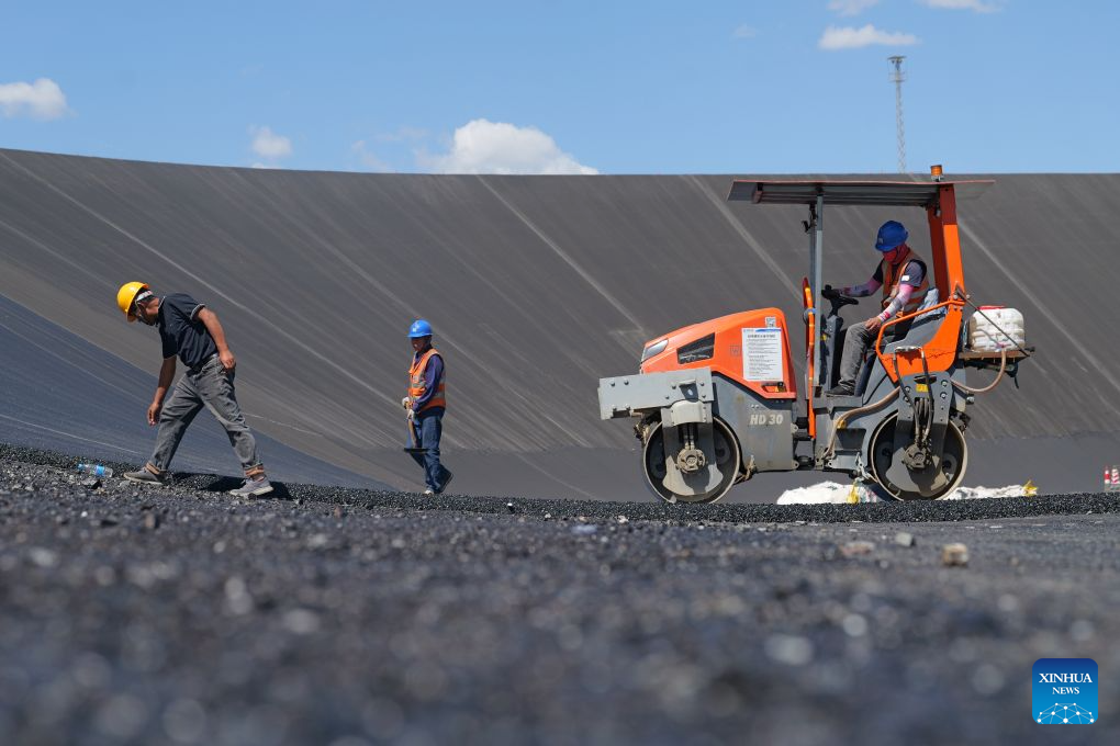 Workers lay asphalt at the construction site of a pumped-storage power station in Zhangye, northwest China's Gansu Province, Aug. 4, 2026. The construction of the power station started in 2022, and all the four 350,000-kW reversible pump-turbine units are expected to be fully put into operation by 2029. (Xinhua/Liu Keying)