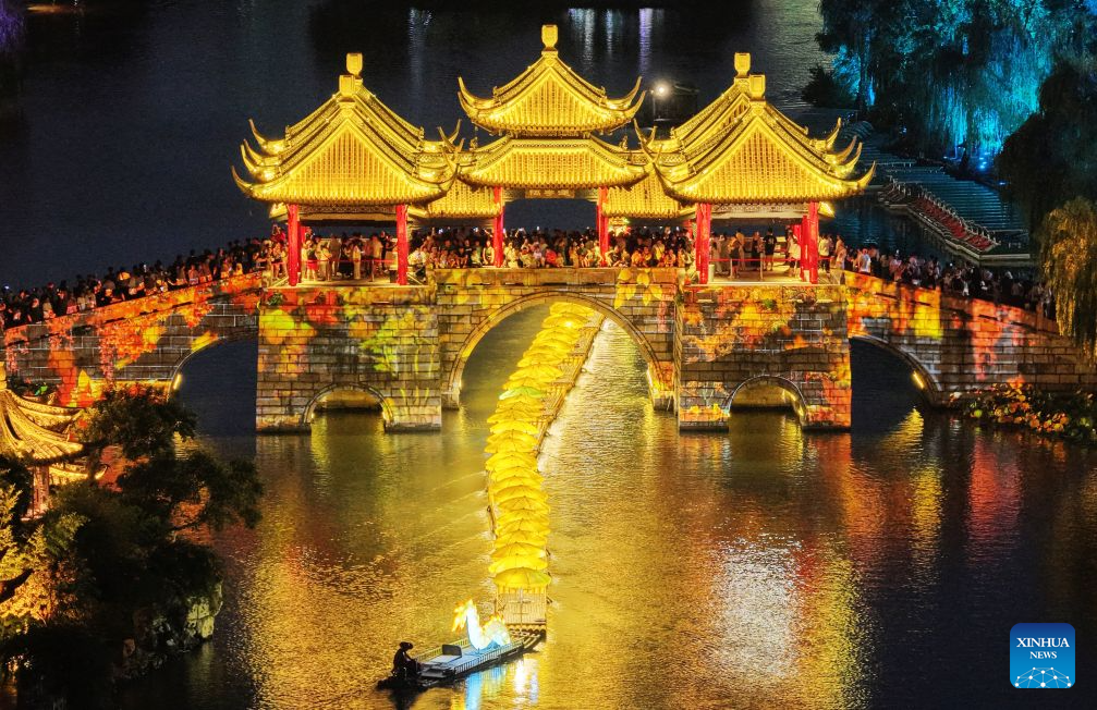 An aerial drone photo taken on Aug. 3, 2026 shows tourists watching a folk show featuring bamboo rafts linking end to end like a golden dragon at the Slender West Lake scenic spot in Yangzhou, east China's Jiangsu Province. (Photo by Meng Delong/Xinhua)