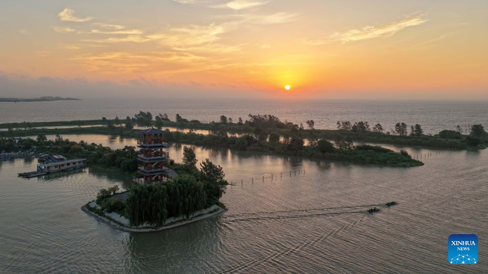 An aerial drone photo taken on Aug. 26, 2026 shows the sunrise scenery at the Hongze Lake Wetland in Sihong County, east China's Jiangsu Province. Hongze Lake Wetland National Nature Reserve, with an area of 750,000 Mu (50,000 hectares), provides vital habitats for birds migrating along the East Asian-Australasian Flyway. In recent years, the nature reserve has seen its number of bird species increase from 147 in 2013 to 240 nowadays, thanks to various environmental protection measures. The total number of birds in the nature reserve has increased to over 800,000. (Photo by Xu Changliang/Xinhua)