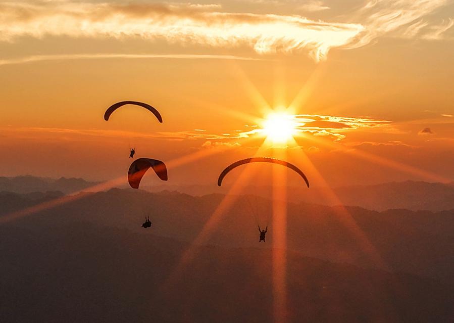 A drone photo taken on July 30, 2026 shows tourists experiencing paragliding with pilots at a paragliding base in Jiuzhou Town, Huangping County, southwest China's Guizhou Province. (Xinhua/Yang Wenbin)