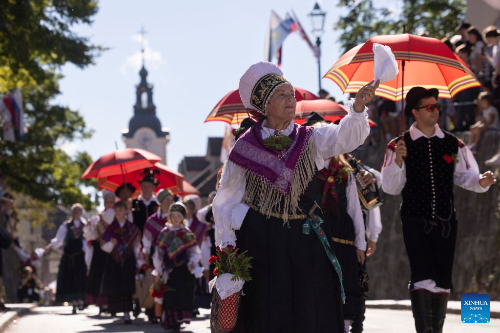 People wearing Slovenian traditional costumes salute the crowd during the parade of the 53rd National Costumes and Clothing Heritage Day in Kamnik, Slovenia, Sept. 13, 2026. The 53rd National Costumes and Clothing Heritage Day ended Sunday in Kamnik with a traditional parade, during which about 2,000 participants dressed in national costumes walked through the center of Kamnik. (Photo by Zeljko Stevanic/Xinhua)