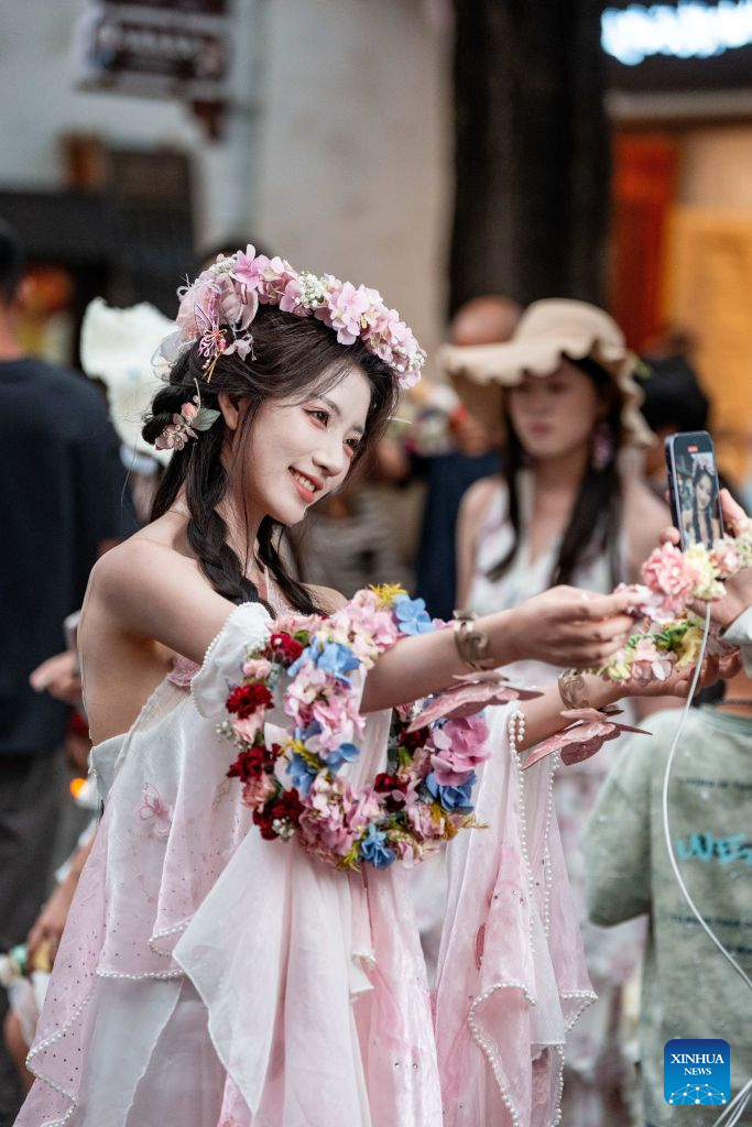 A woman shoots a video of herself at the ancient town of Dali in Dali, southwest China's Yunnan Province, Aug. 22, 2026. The ancient town of Dali has entered its peak tourism season during the summer holiday. According to the ancient town protection and management department, the ancient town recorded over 22 million tourist trips in the first seven months of 2026. (Xinhua/Hu Chao)