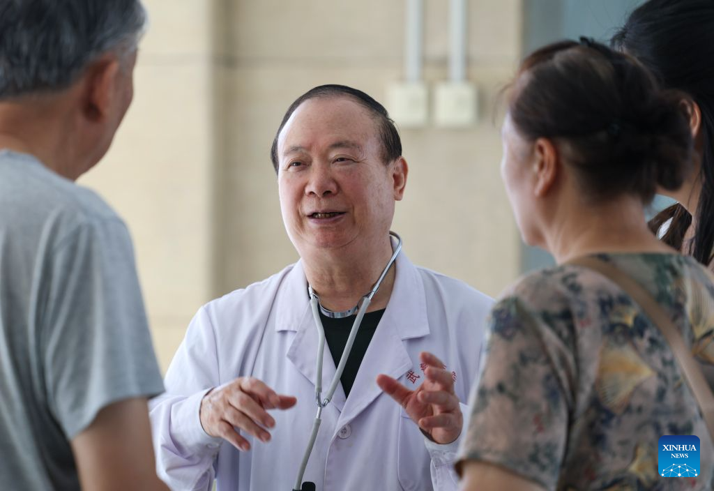 Zhuang Shihua talks with a patient and his family at the hospital affiliated to the Xinjiang Armed Police Corps in Urumqi, northwest China's Xinjiang Uygur Autonomous Region, Aug. 18, 2026. (Xinhua/Wang Fei)