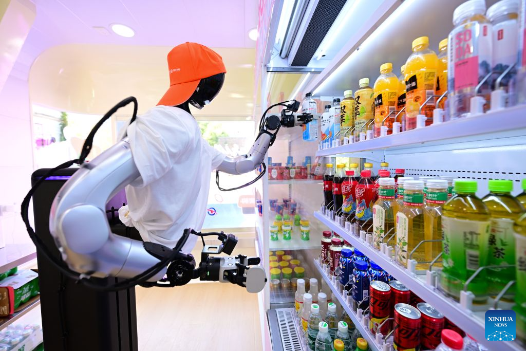 A robot grabs a bottle of electrolyte water from the shelf at an embodied intelligence robot store at Leijie Street in Hefei, east China's Anhui Province, Aug. 26, 2026. Four embodied intelligence robot stores equipped with wheeled humanoid robot shop assistants have officially opened in several cultural, tourism and commercial blocks in Hefei. The robot shop assistants are able to automatically recognize, grab and deliver merchandise to customers. (Xinhua/Zhou Mu)