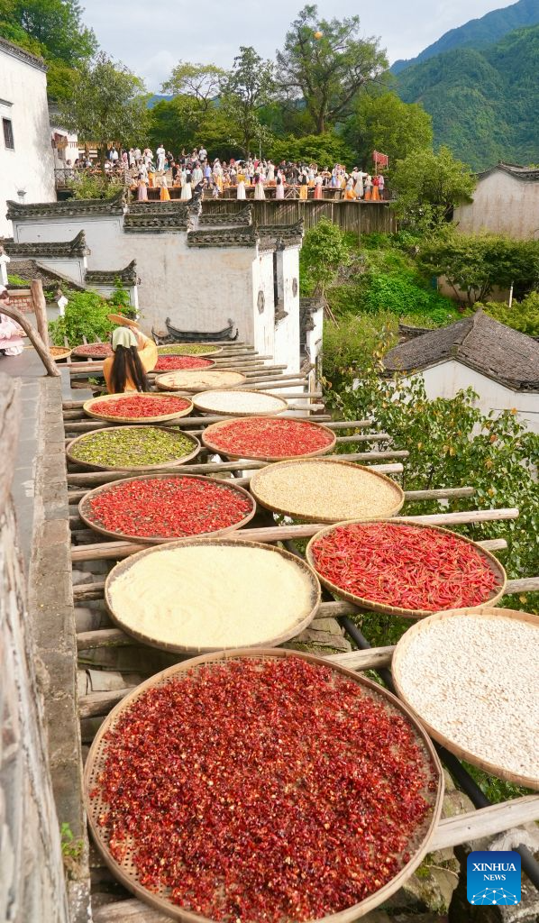 This photo taken on Aug. 25, 2026 shows a view of Huangling Village in Wuyuan County, east China's Jiangxi Province. As early autumn sets in, villagers in Huangling spread harvested crops on bamboo trays to dry. Colorful drying trays form a striking contrast against Hui-style houses with white walls and black tiles, drawing crowds of tourists. (Xinhua/Hu Chenhuan)
