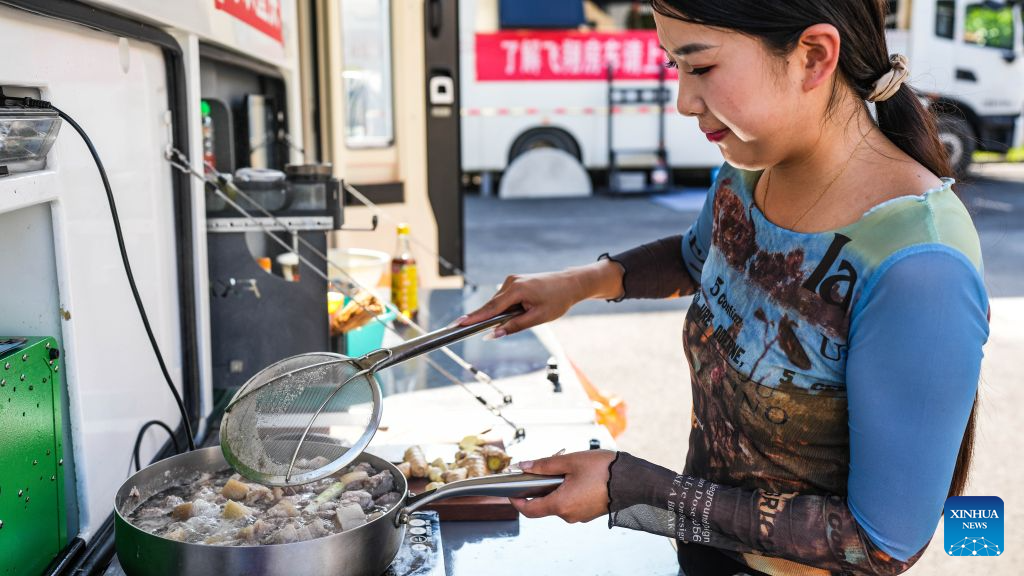 A camper cooks dinner at a RV (recreational vehicles) camping base in Bijie City, southwest China's Guizhou Province, Aug. 11, 2026. In recent years, Bijie City has leveraged its scenic natural environment and pleasant mountain climate to promote the development of RV camping bases and boost summer tourism, drawing RV travelers from across China. (Xinhua/Tao Liang)