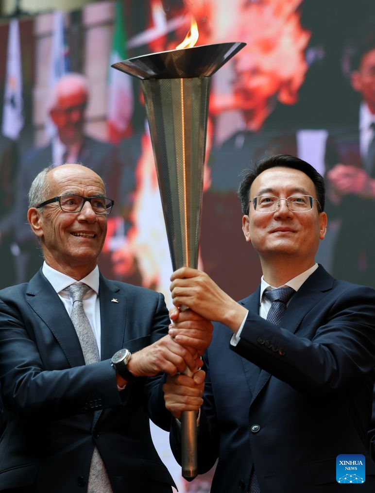 Mayor of Changchun Gu Gang (R) and president of FISU Leonz Eder hold the torch from the first World University Games held in Turin in 1959 during the flame collection ceremony for the Changchun 2027 Winter Universiade in Turin, Italy, Oct. 8, 2026. (Xinhua/Wang Kaiyan)