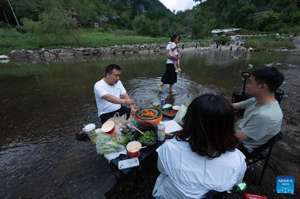 Tourists picnic in the shallows of a stream in Zengjiashan scenic spot of Guangyuan City, southwest China's Sichuan Province, Aug. 23, 2026. Zengjiashan, a summer getaway with an average elevation of 1,300 meters and summer temperatures of around 23 degrees centigrade, is developing tourism by making the most of its cool climate, attracting visitors from surrounding areas. (Xinhua/Jiang Hongjing)