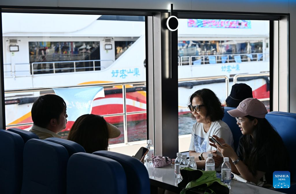 Tourists enjoy their leisure time by boat in Qingdao, east China's Shandong Province, Aug. 26, 2026. The Qingdao Olympic Sailing and Marine Culture Tourism Area has been promoting sea sightseeing by launching a number of sightseeing routes linking destinations from Jiaozhou Bay to Zhaitang Island, helping boost local tourism. (Xinhua/Li Ziheng)