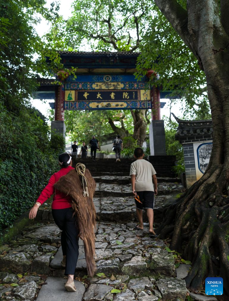 This photo taken on July 26, 2026 shows local residents walking in Lushi ancient town in Fengqing County of Lincang City in southwest China's Yunnan Province. Lushi ancient town in the northeast of Fengqing County lies between the Lancang River and Heihui River. Due to its special geographical location, Lushi was once an important trading hub on the ancient Tea Horse Road, a trade route dating back to the Tang Dynasty (618-907). The town has formed an unique culture that is influenced by merchants coming and going as well as multi-ethnic cohabitation. (Photo by Lan Hongguang/Xinhua)