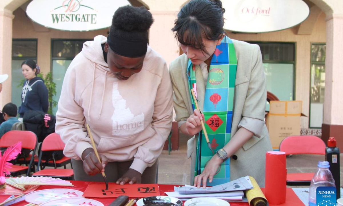 A local woman (L) tries her hand at Chinese calligraphy during the Asian Cultural Festival 2026 in Harare, Zimbabwe, on Aug. 1, 2026.  (Photo by Tafara Mugwara/Xinhua)