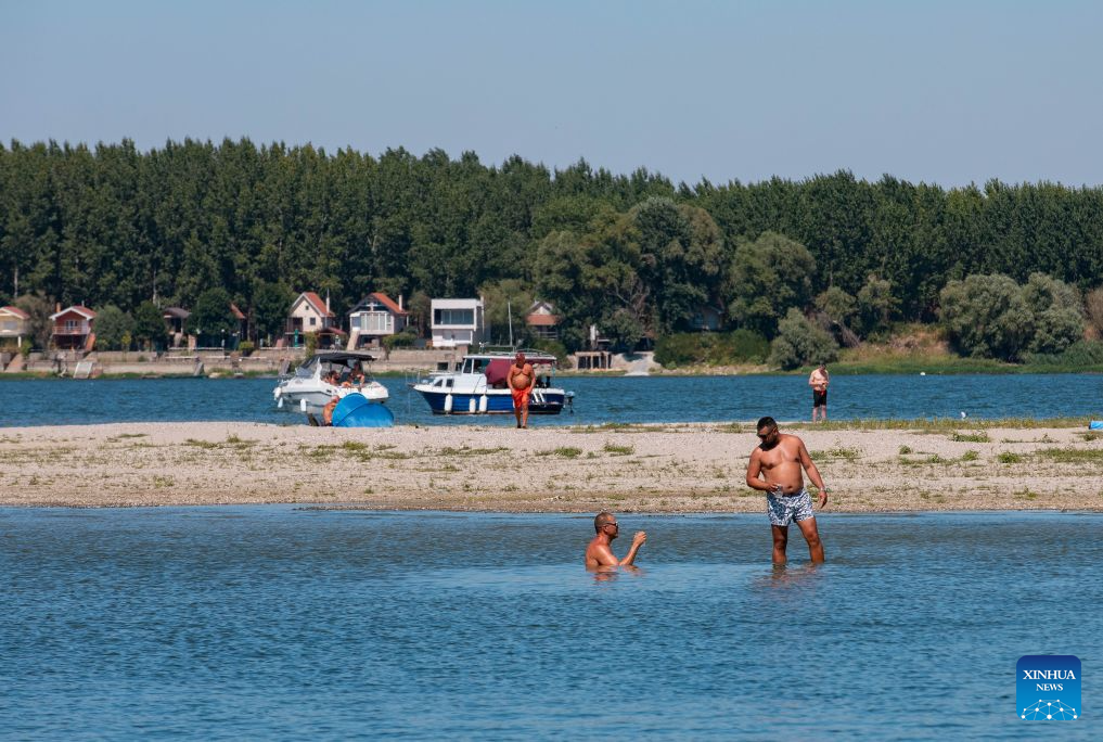 People cool off in the Danube River in Belgrade, Serbia, on Aug. 16, 2026. Riverbed was exposed as the water level of the Danube River approached record-low by severe drought. (Photo by Wang Wei/Xinhua)