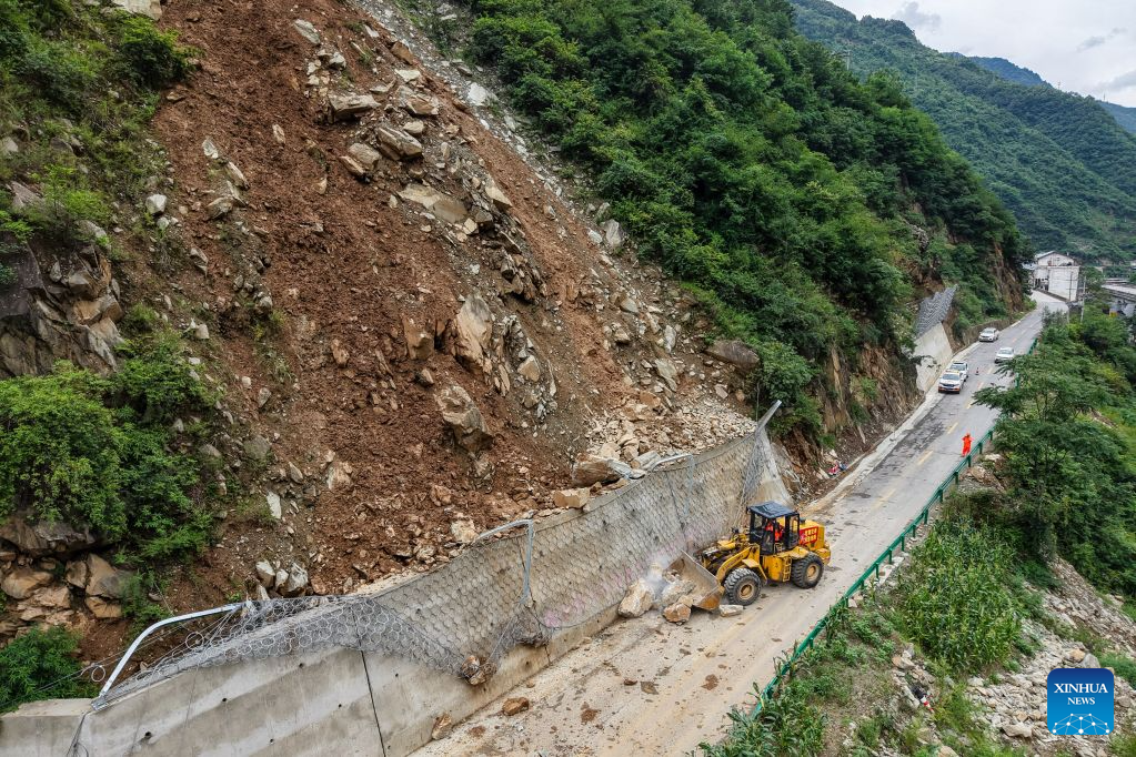 A drone photo taken on Aug. 2, 2026 shows staff members clearing a road blocked by a landslide in Caoping Village of Fengxiang Township in Longnan, northwest China's Gansu Province. Longnan in northwest China's Gansu Province has activated Level II emergency response for flood control due to widespread heavy rainfall since Wednesday. Authorities at different levels have carried out inspections and assessments for potential hazards and repairs of damaged infrastructure, so as to safeguard people's lives and property. (Xinhua/Lang Bingbing)