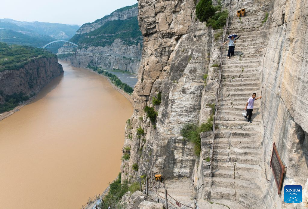 An aerial drone photo taken on Aug. 10, 2026 shows tourists visiting a scenic area along the Yellow River in north China's Shanxi Province. With the completion and operation of transport infrastructure, such as the Yanhuang Highway in northwest China's Shaanxi Province and the Yellow River No.1 Tourist Highway in north China's Shanxi Province, tour along the Yellow River has become a popular choice for many travelers in summer. (Xinhua/Shao Rui)