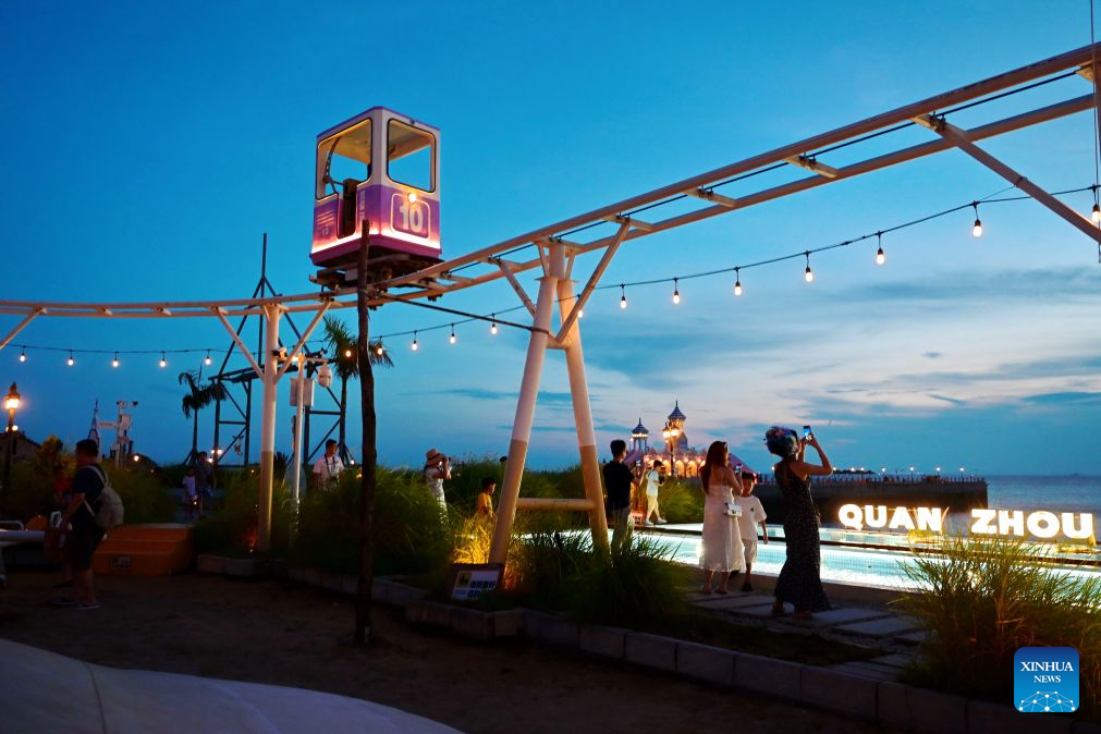 People enjoy a night view at the Chongwu ancient ferry terminal scenic area in Hui'an County of Quanzhou, southeast China's Fujian Province, Aug. 17, 2026. The Chongwu ancient ferry terminal covers an area of 33 mu (about 2.2 hectares) in Hui'an County of southeast China's Fujian Province. In 2024, local authorities transformed it from an idle terminal into a coastal vacation destination that integrates art galleries, a pier runway, trendy restaurants, and family playgrounds. (Xinhua/Lin Shanchuan)