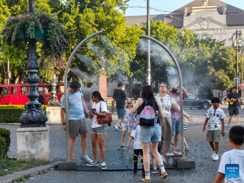 People cool off under a misting system in Bratislava, Slovak, Aug. 11, 2026. This summer was the third-warmest recorded in Slovakia since 1931, the Slovak Hydrometeorological Institute (SHMU) said on Friday.(Xinhua/Liu Haodong)