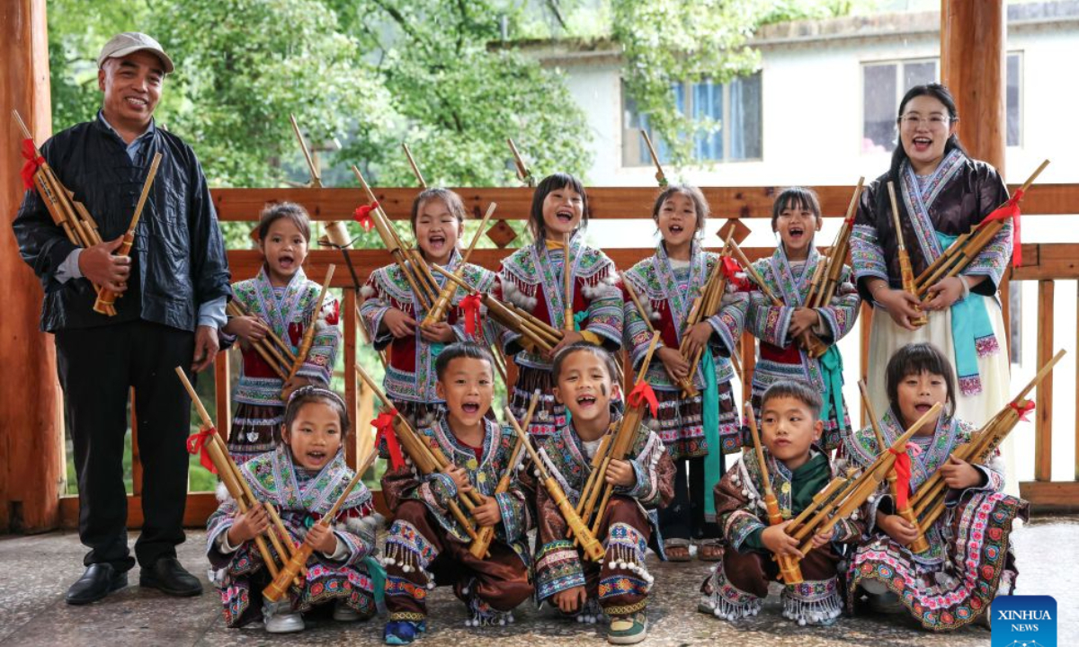 Pan Xianfeng (1st L) and Peng Hanping (1st R) pose for a group photo with students at the Wuying teaching site in Wuying Village on the border between south China's Guangxi Zhuang Autonomous Region and southwest China's Guizhou Province, Sept. 4, 2026.(Xinhua/Yang Wenbin)