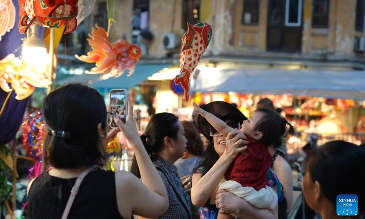 A child touches a fish-shaped lantern at the Old Quarter in Hanoi, Vietnam, Sept. 22, 2026. A festive atmosphere is growing here as the Mid-Autumn Festival approaches. (Xinhua/Liu Ying)