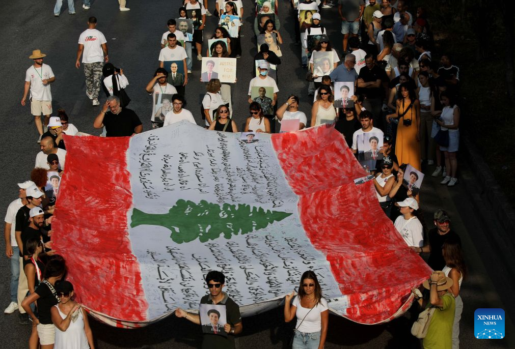 People hold a national flag and portraits of the victims in commemoration of the sixth anniversary of the 2020 Beirut port blasts in Beirut, Lebanon, Aug. 4, 2026. (Xinhua/Bilal Jawich)