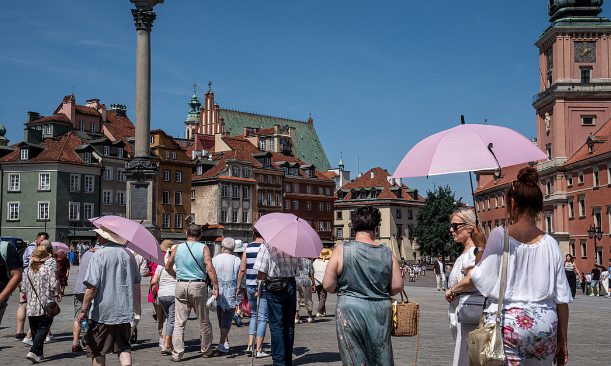 Tourists use umbrellas for shade while visiting Castle Square in the Old Town district during high temperatures in Warsaw, Poland, on June 30, 2026. Red warnings for extreme heat have been issued in several countries, including Poland, Hungary, Romania, and Croatia, with similar alerts still in place for parts of southern and western Switzerland. Photo: VCG