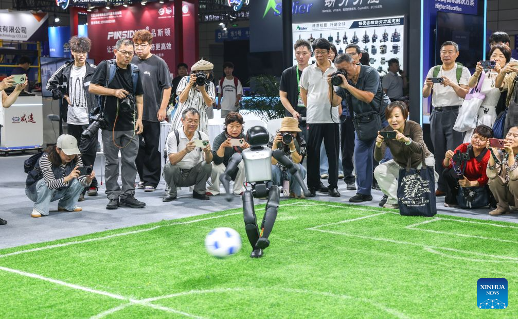 Visitors watch a robot playing football at the 2026 World Manufacturing Convention (WMC) in Hefei, east China's Anhui Province, Sept. 21, 2026. The ongoing 2026 WMC showcases wide-ranging applications of robots. (Xinhua/Chang Nengjia)