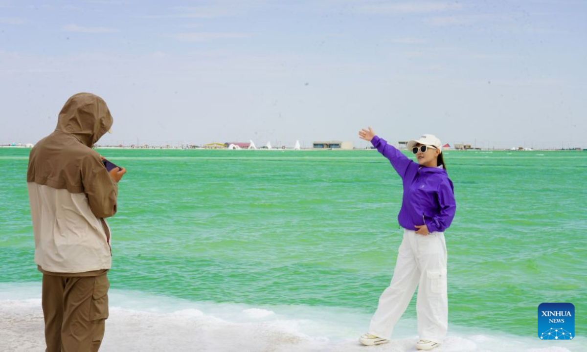 Tourists visit the Qairhan salt lake in Golmud, northwest China's Qinghai Province, July 9, 2026. The Qairhan salt lake, with a total area of 5,856 square kilometers, has been the largest potash fertilizer producing base in China. (Xinhua/Wang Yan)